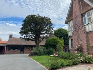 une maison en briques avec un arbre dans la cour dans l'établissement Au Petit Manoir, à Socx