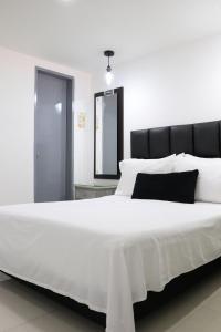 1 cama blanca grande con cabecero negro y almohadas blancas en Moblat MED, en Medellín