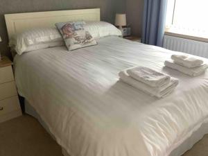 Una cama blanca con toallas encima. en Carrick House, Mid-Ulster en Knockloughrim