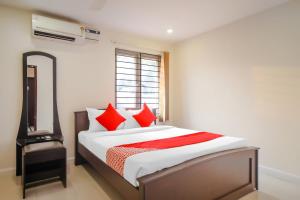 Pride Hospitality Nungambakkam في تشيناي: غرفة نوم بسرير ومخدات حمراء ومرآة