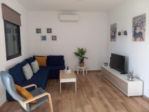 sala de estar con sofá azul y TV en Casa Rosalinda, en Conil de la Frontera