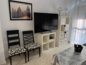 sala de estar con 2 sillas y TV de pantalla plana en Casa Luz y Azahar en San Juan del Puerto