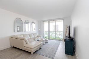 a white living room with a couch and a tv at Stunning & Spacious Resort-Style Condo Across From Beach! in Miami Beach