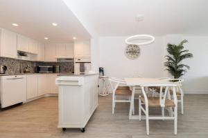 a kitchen with white cabinets and a white table and chairs at Stunning & Spacious Resort-Style Condo Across From Beach! in Miami Beach