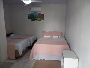 two beds in a small room with pink sheets at HELLO MT POUSADA in Nobres