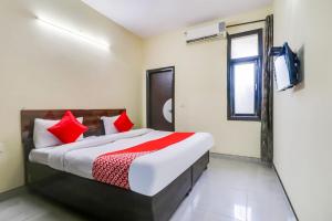 a bedroom with a bed with red pillows and a television at OYO 74753 Sushma Ssadan in New Delhi