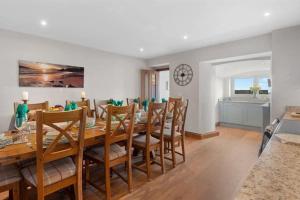 uma sala de jantar com uma longa mesa de madeira e cadeiras em Edith Villas - Luxury seaside home with beautiful sea views-Pendine em Pendine