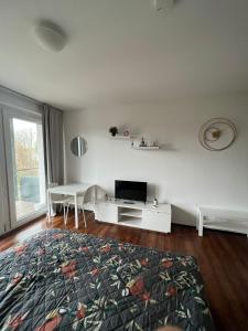 a white living room with a tv and a table at Ferienwohnung Köln in Cologne