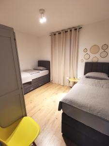 1 dormitorio con 2 camas y silla amarilla en Villa Calendula, en Novigrad (Dalmacia)