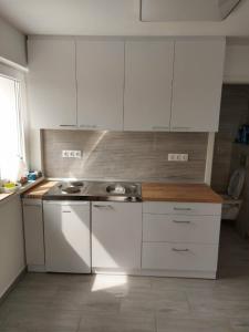 una cocina con armarios blancos y fregadero en Apartman for You en Gyenesdiás