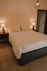 1 dormitorio con 1 cama blanca grande y 2 lámparas en Lahos Apartament's, en Panajachel