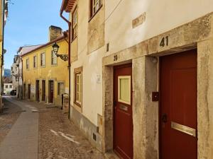 a street in an old town with red doors at Alta apartments in Coimbra