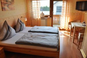 Bett in einem Zimmer mit einem Tisch und einem Fenster in der Unterkunft Pension Jonas in Baar