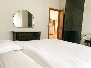 un letto bianco in una camera da letto con specchio di Bernina Views-Tirano a Tirano