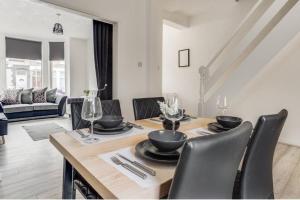 a dining room with a wooden table and black chairs at Liverpool 3 bed house (free parking) in Liverpool