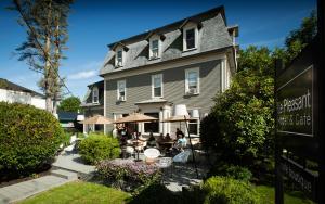 a building with people sitting at tables in front of it at Le Pleasant Hôtel & Café in Sutton