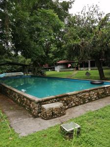 une piscine entourée d'un mur en pierre dans l'établissement Waterfall Hostel, à Los Anastacios