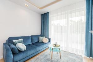 a living room with a blue couch and a table at Flatbook Apartamenty - Jantar Bursztynowe Osiedle in Jantar