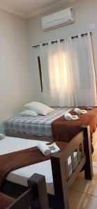 um quarto com 2 camas e uma janela com uma ventoinha em Angelo Hotel em Olímpia