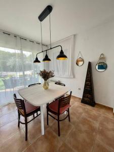 une salle à manger avec une table et des chaises blanches dans l'établissement Casa con piscina Sant Pol de Mar, à San Pol de Mar