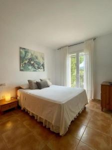 a bedroom with a large white bed with a window at Casa con piscina Sant Pol de Mar in San Pol de Mar