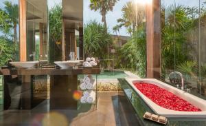 a bathroom with two sinks and a tub of red roses at iVilla by Ekosistem in Seminyak