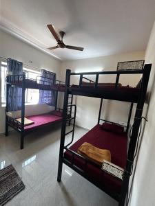 a room with three bunk beds and a ceiling fan at Lostel Gokarna in Gokarna