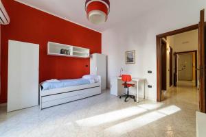 a bedroom with a red wall with a bed and a desk at [Casa vacanze “In Centro”] in Salerno