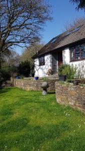 a house with a stone wall in front of a yard at Meadow Oak Accommodation in Bodmin