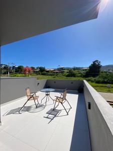 um pátio com 2 cadeiras e uma mesa no telhado em Casa de hóspede Dunas do Siriú em Garopaba