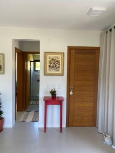 um quarto com uma mesa vermelha e uma porta de madeira em Casa de hóspede Dunas do Siriú em Garopaba