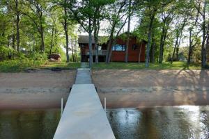 a dock in front of a house next to the water at Dog Friendly Leech Lake Home w Perfect Beach Garage Boat Lift in Walker