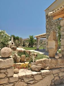 una pared de piedra frente a una casa con jardín en villa Armonia with heating pool -Pitsidia, Matala, Kalamaki, en Pitsidia 24 fotos más