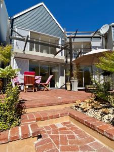 a house with a patio with chairs and an umbrella at 42 Spinnaker, The Quays in Knysna