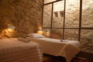 1 dormitorio con 2 camas y pared de piedra en Dana Gardens Hotel en Ḑānā