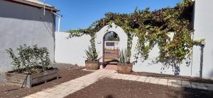 a white wall with an arch and potted plants at Farmhouse Guestrooms in Calitzdorp