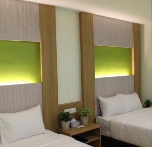 2 łóżka w pokoju zielonym i białym w obiekcie Xpeed Holiday Hotel w Kuala Lumpur