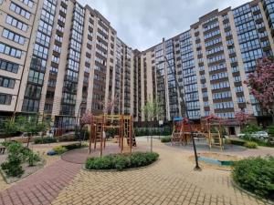 um parque infantil em frente a um grande edifício de apartamentos em VIP APARTMENTs em Lutsʼk