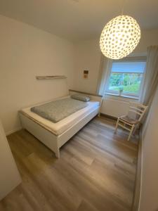 a bedroom with a bed and a chair and a chandelier at Ferienwohnung „Maya“ in Langelsheim