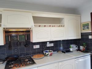 a kitchen with white cabinets and a stove top oven at Meadow Oak Accommodation in Bodmin