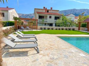 - un groupe de chaises longues à côté de la piscine dans l'établissement Apartment Baska mit Poolarea - Krk, Kroatien, à Baška