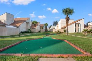 a golf course with a palm tree and houses at Chic Townhouse Steps to the Beach Outdoor Pools in Panama City Beach