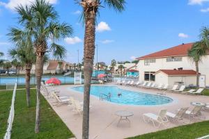 a pool with chairs and palm trees in a resort at Chic Townhouse Steps to the Beach Outdoor Pools in Panama City Beach