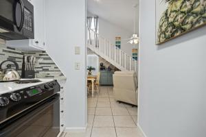 a kitchen with a stove and a microwave at Chic Townhouse Steps to the Beach Outdoor Pools in Panama City Beach