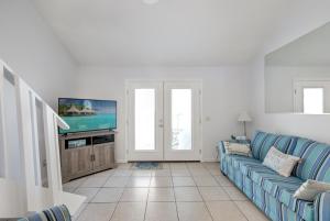 a living room with a blue couch and a tv at Chic Townhouse Steps to the Beach Outdoor Pools in Panama City Beach
