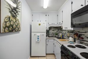 a kitchen with white cabinets and a refrigerator at Chic Townhouse Steps to the Beach Outdoor Pools in Panama City Beach