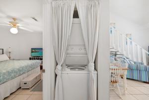 a white room with a bed and a room with a table at Chic Townhouse Steps to the Beach Outdoor Pools in Panama City Beach