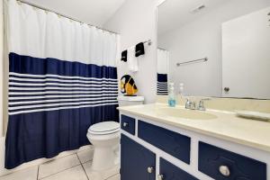 a bathroom with a blue and white shower curtain and a toilet at Chic Townhouse Steps to the Beach Outdoor Pools in Panama City Beach