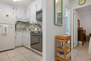 a kitchen with white cabinets and a white refrigerator at Chic Townhouse Steps to the Beach Outdoor Pools in Panama City Beach