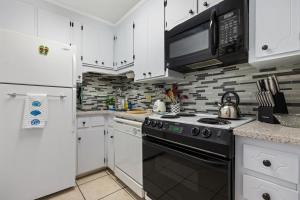 a kitchen with white cabinets and a black stove top oven at Chic Townhouse Steps to the Beach Outdoor Pools in Panama City Beach